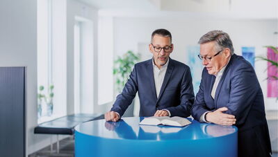 Kanzlei für Steuerberatung und Wirtschaftsprüfung Zwei Männer unterhalten sich an einem Tisch